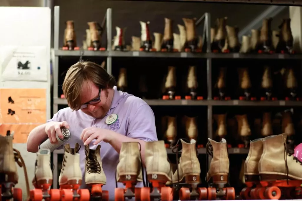 An intellectually disabled employee cleans roller skate rentals at a skating rink.