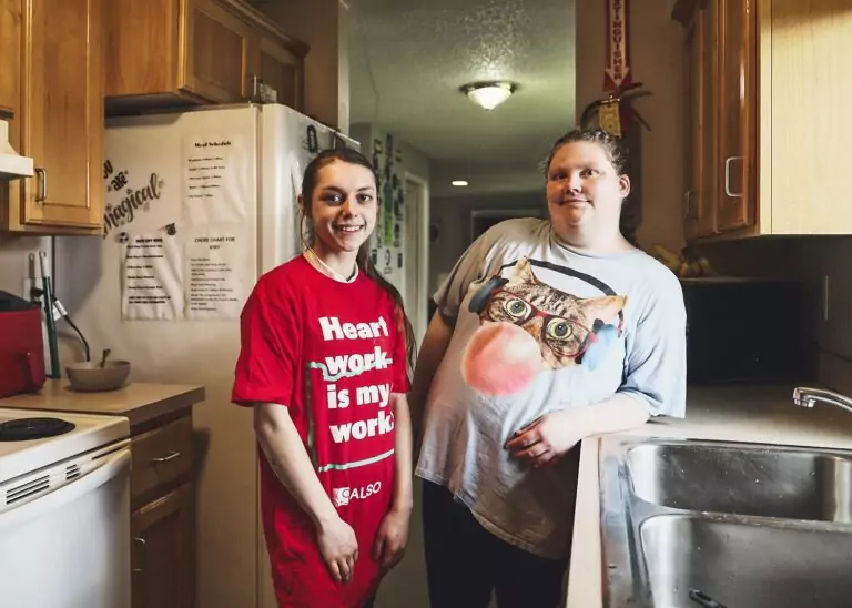 A developmentally disabled young woman and a DSP worker stand in a kitchen together. 