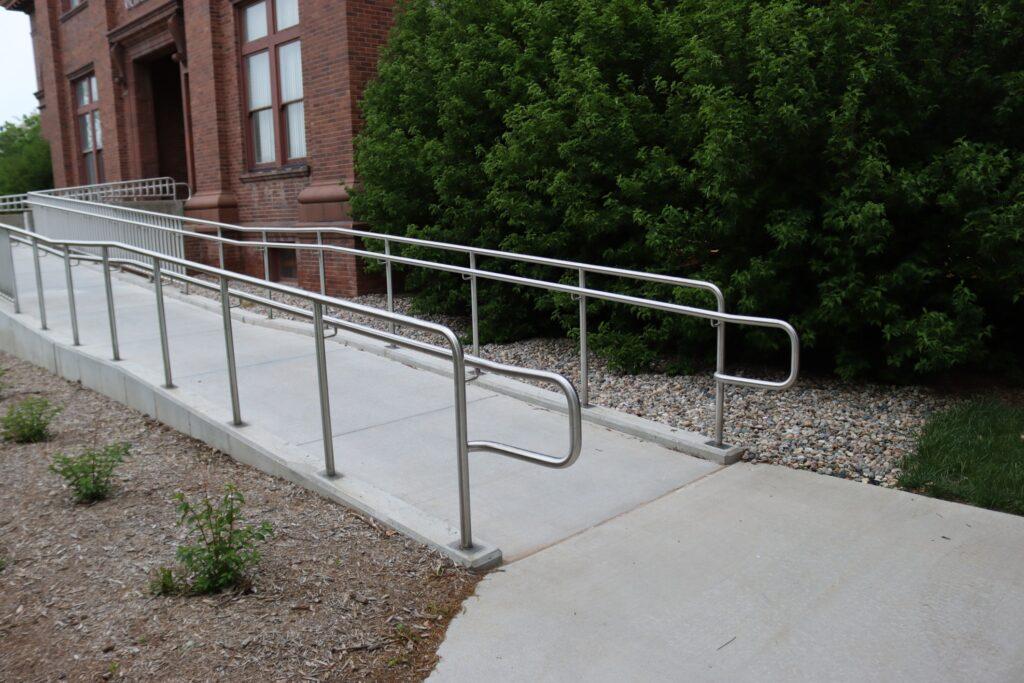 A wheelchair ramp going up to the front entrance of a brick office building. 