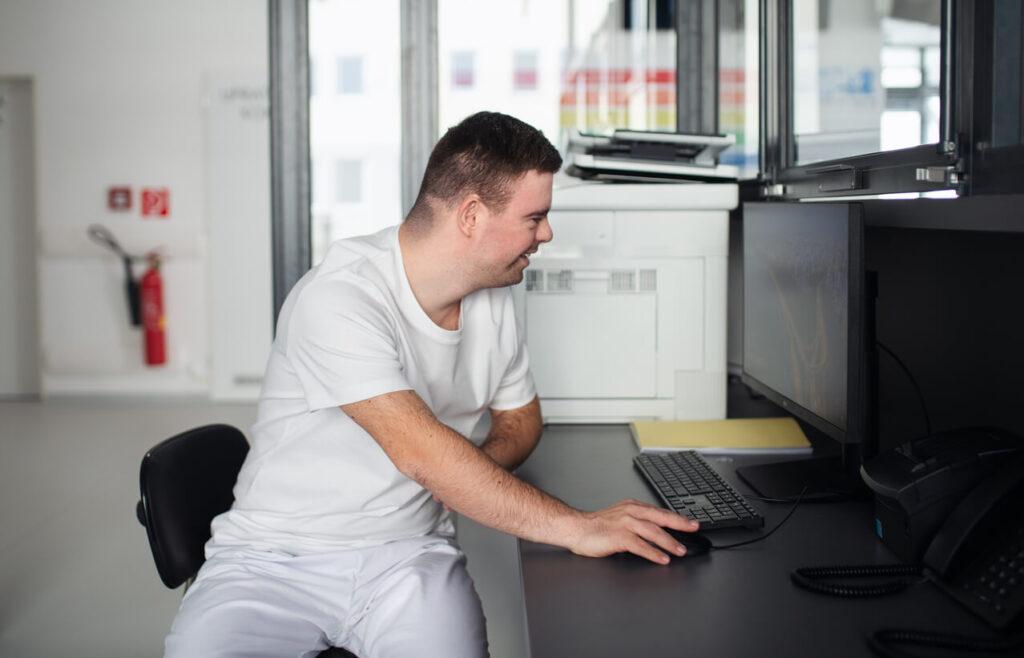 Person with an intellectual or developmental disability works on a computer in an office.
