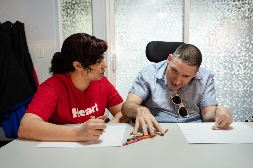 An ALSO DSP sitting at a a table and working with a developmentally disabled individual to set up an ABLE account. 