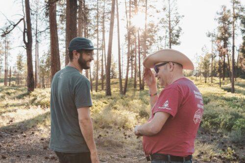 A direct support professional laughs with an intellectually disabled person during a hike on a trail in Oregon.