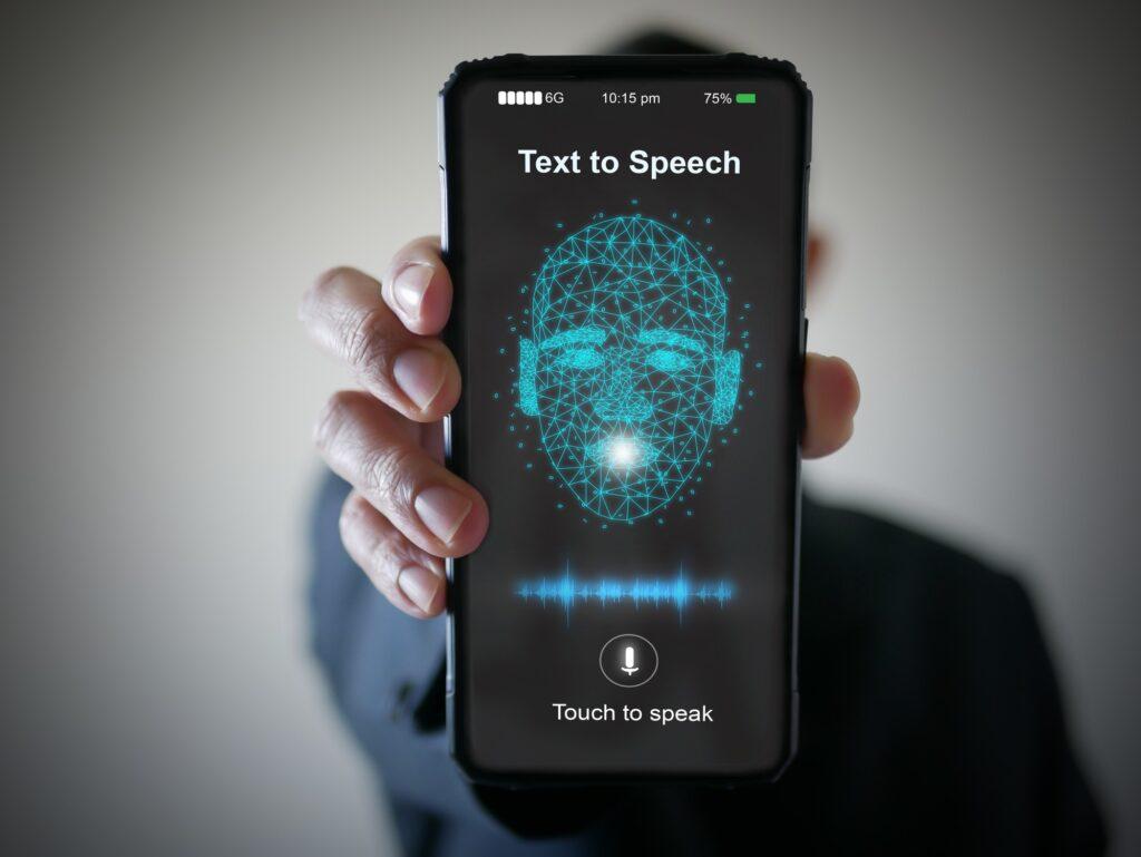 A hand holding up a mobile phone with text to speech on it.