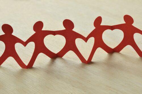 A string of red paper doll cutouts signifying working together to make an impact.