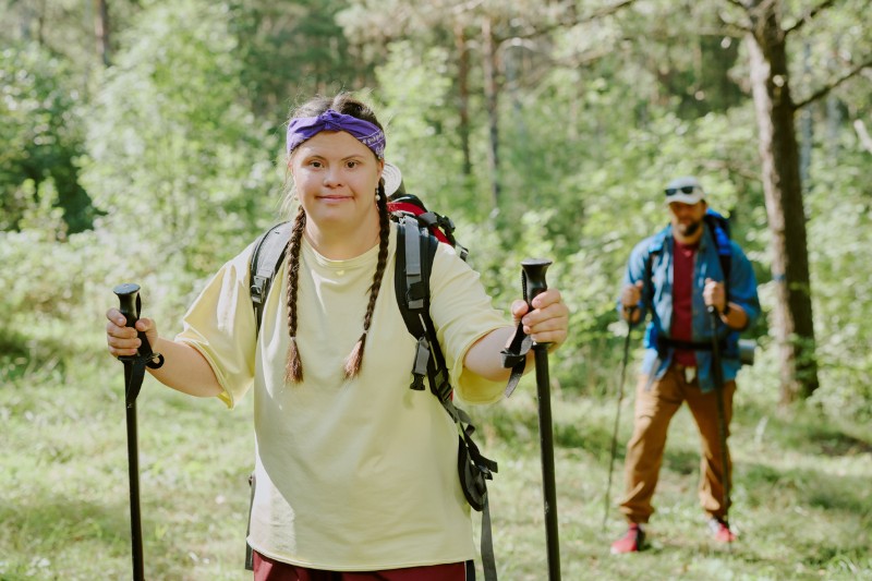 A young woman with I/DD hikes with poles. 