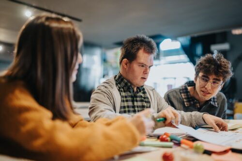 Three developmentally disabled students work on a class high school project.